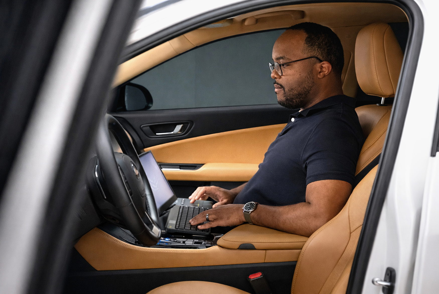 Engineer developing vehicle software inside car using laptop