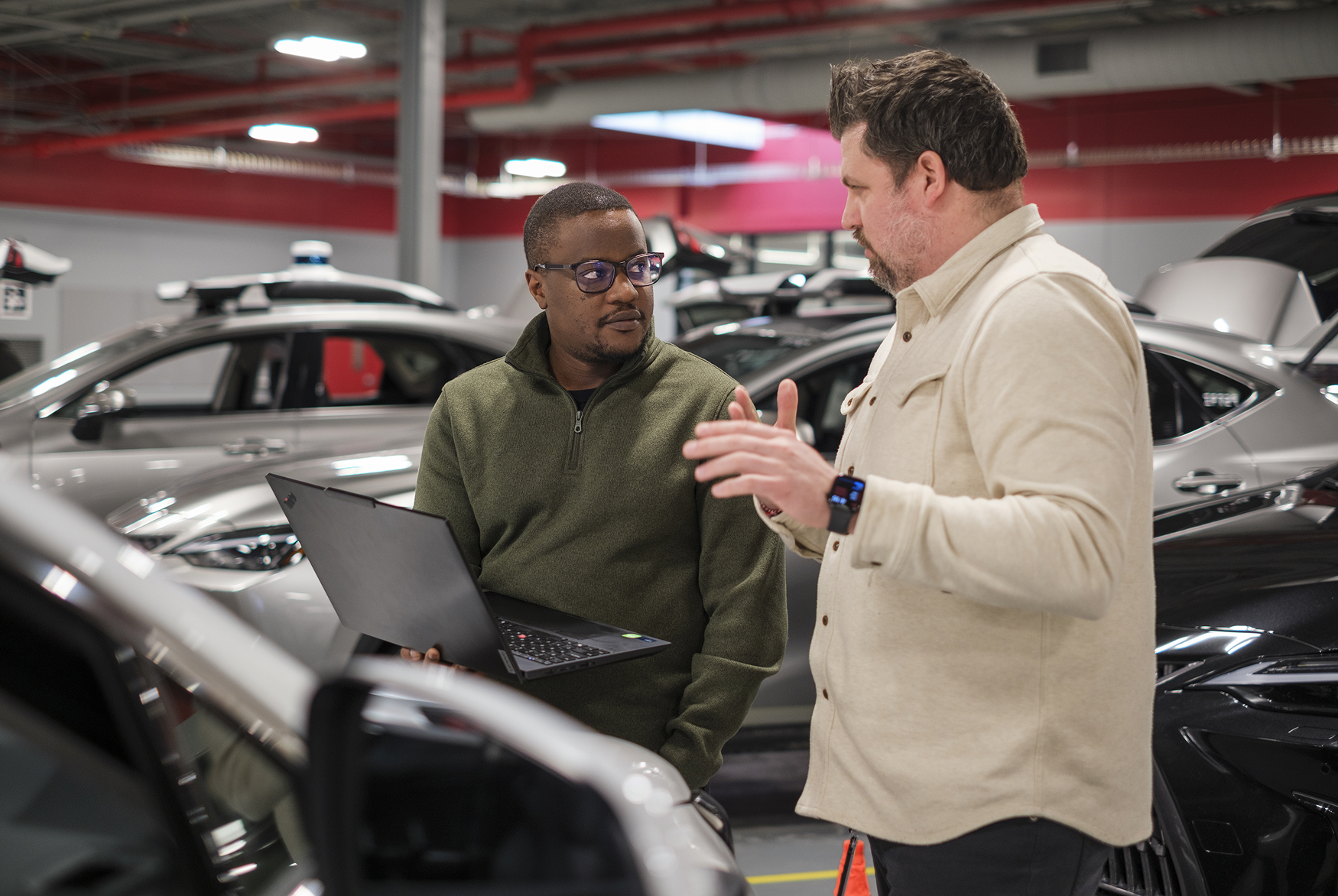 Engineers reviewing vehicle data and systems in garage environment with connected vehicles