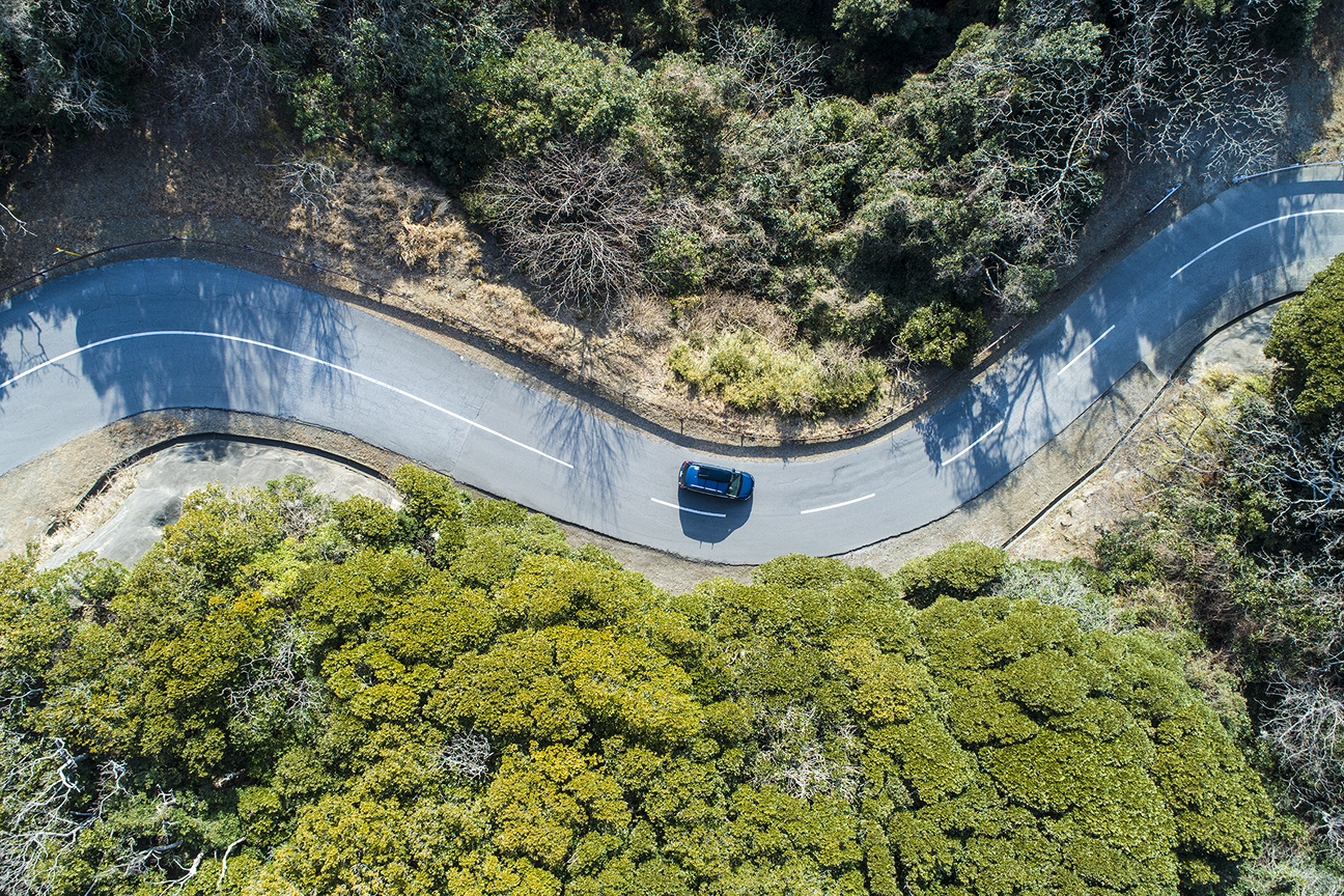 Aerial view of vehicle navigating winding road through natural landscape