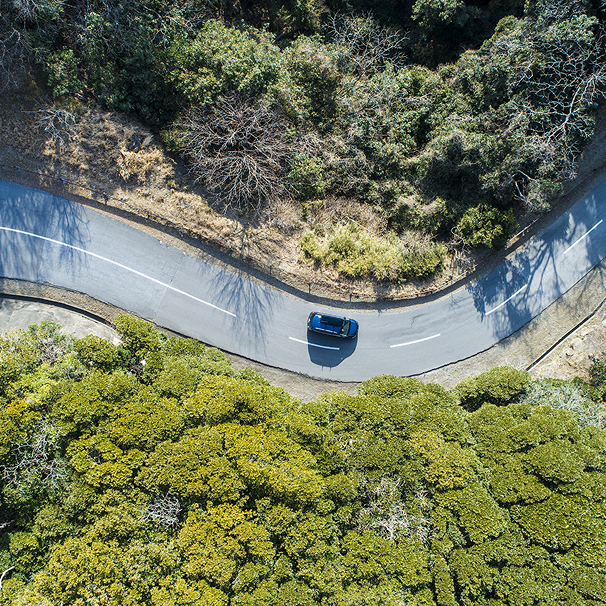 Aerial view of vehicle navigating winding road through natural landscape